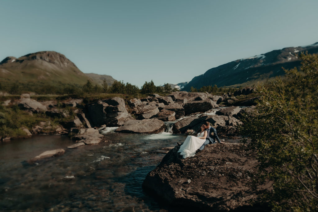 Wedding couple sitting by a river enjoying some quit time in Norway