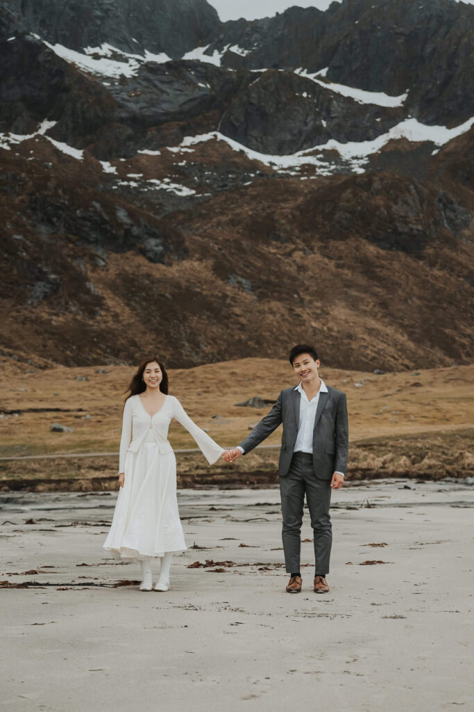 Elopement couple holding hands on a beach in Lofoten