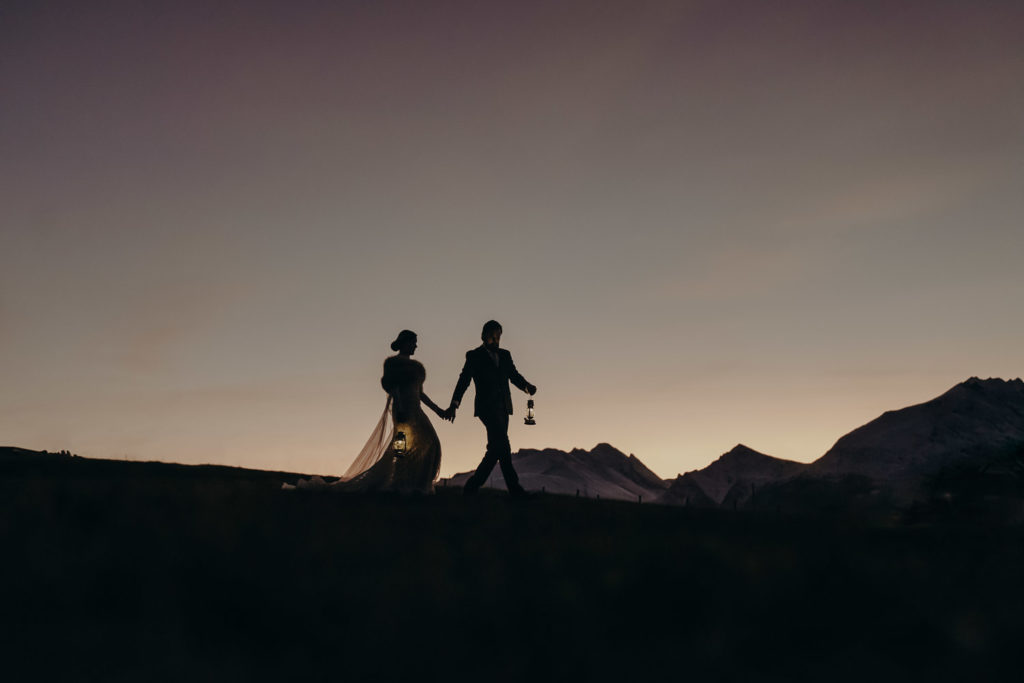 A silhouette image of a wedding couple walking in stunning light right after sunset. 