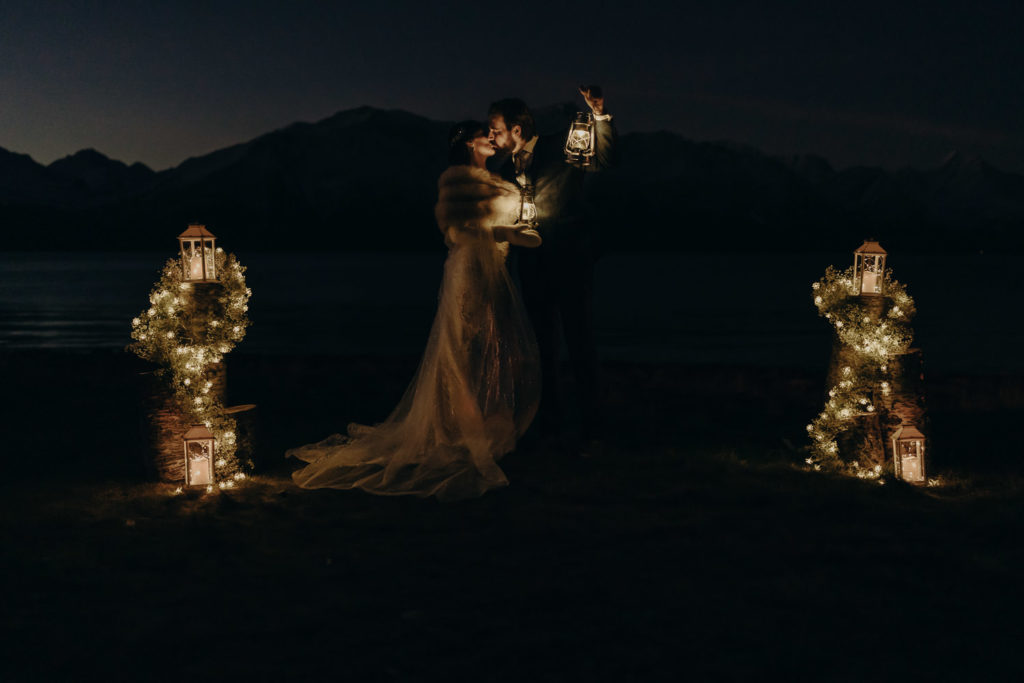 Wedding couple kissing at night in the light from lanterns