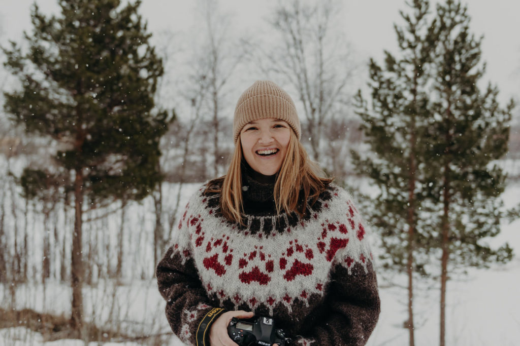 A female photographer smiling at the camera in a snowy landscape