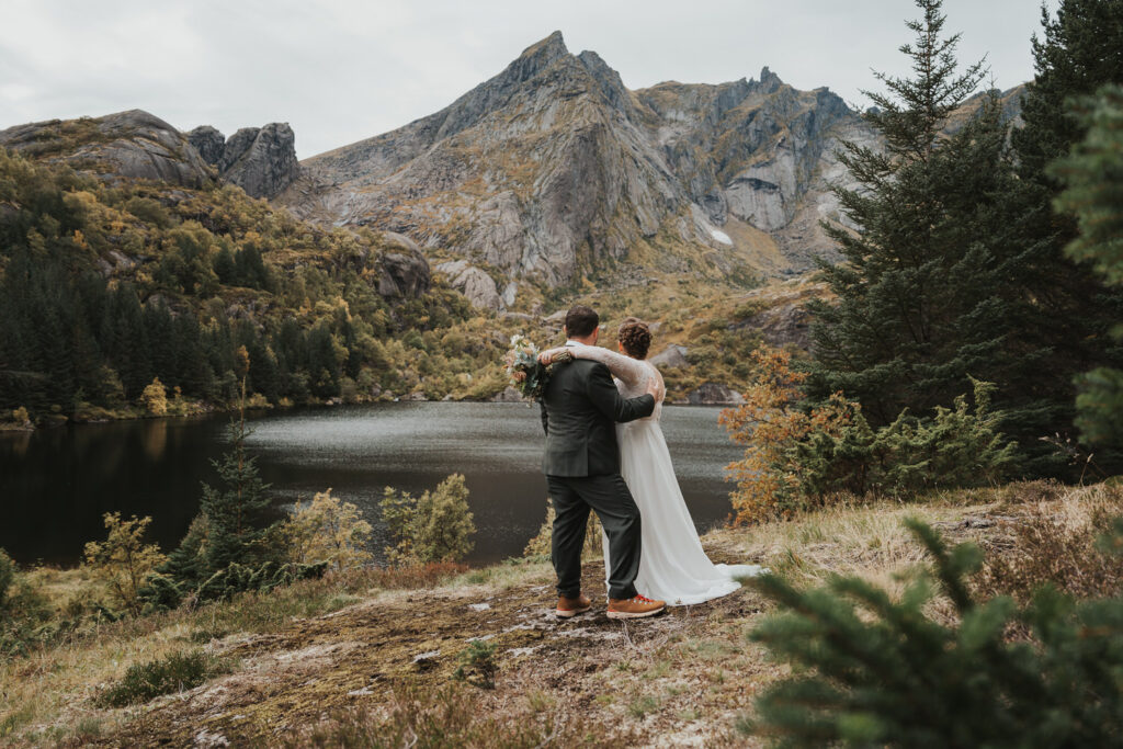 Elopement couple embracing while looking at high mountains in Lofoten