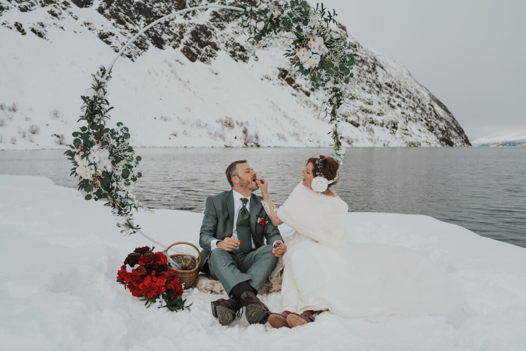 Bride and groom picnic in snow during winter wedding in Norway