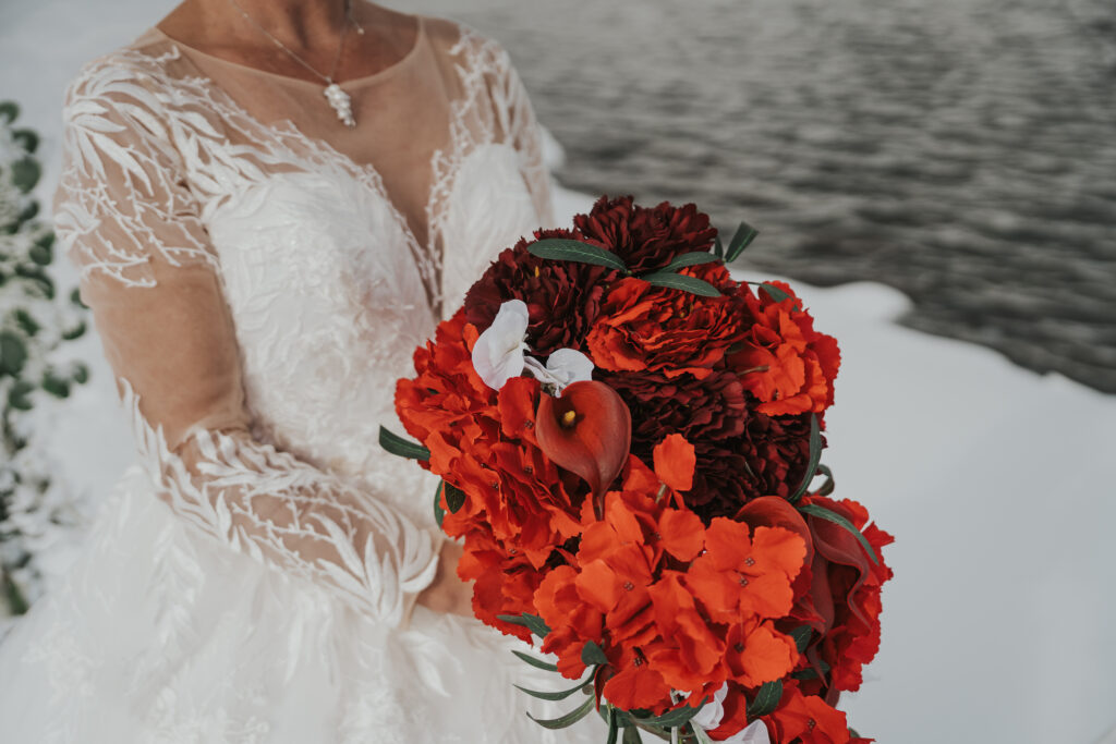 Bride with red flowers during winter elopement in Lyngen, Northern Norway