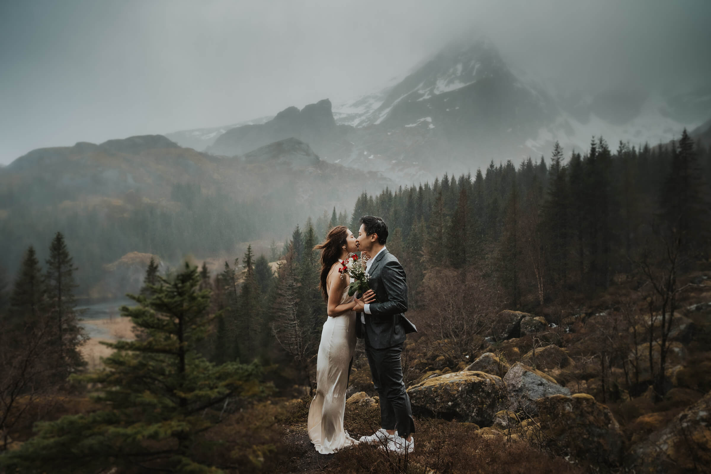 Elopement couple kissing in the rain on a mountain in a rainy Lofoten